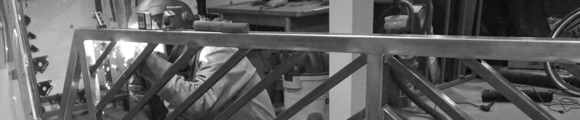 A close-up view of welding the Mini Dome custom steel railing in black and white.