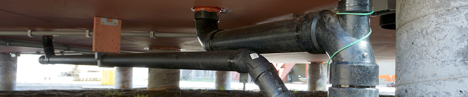 A close-up view of the pipes and conduit under the floor of the Mini Dome.